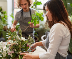Foto: ein junges Floristenteam (ein Mann und eine Frau) beim Blumenstrauß binden. 