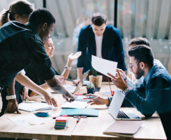 Foto: ein diverses Team an Ausbilder/-innen oder Lehrkräften bei einem Meeting.