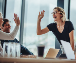 Foto: eine lächelnde Ausbilderin oder Lehrerin hat die Hand in der Luft um der Kollegin ein High-Five zu geben. 