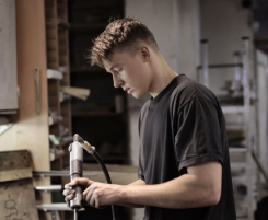 Foto: ein Auszubildender mit Werkzeug in der Hand.