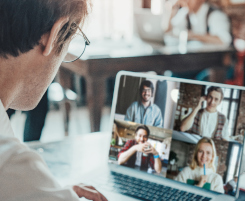 Foto: Ein Mann sitzt vor einem Laptap. Auf dem Laptop-Bildschirm sind vier Kacheln mit den Bildern der Online-Workshop-Teilnehmenden zu sehen.