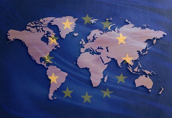 Auf dem Bild ist die Weltkarte grafisch dargestellt. Über ihr schein die europäische Flagge leicht durch.
